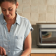 A person prepping food in a kitchen with the new Brava Glass smart oven behind them on a counter.